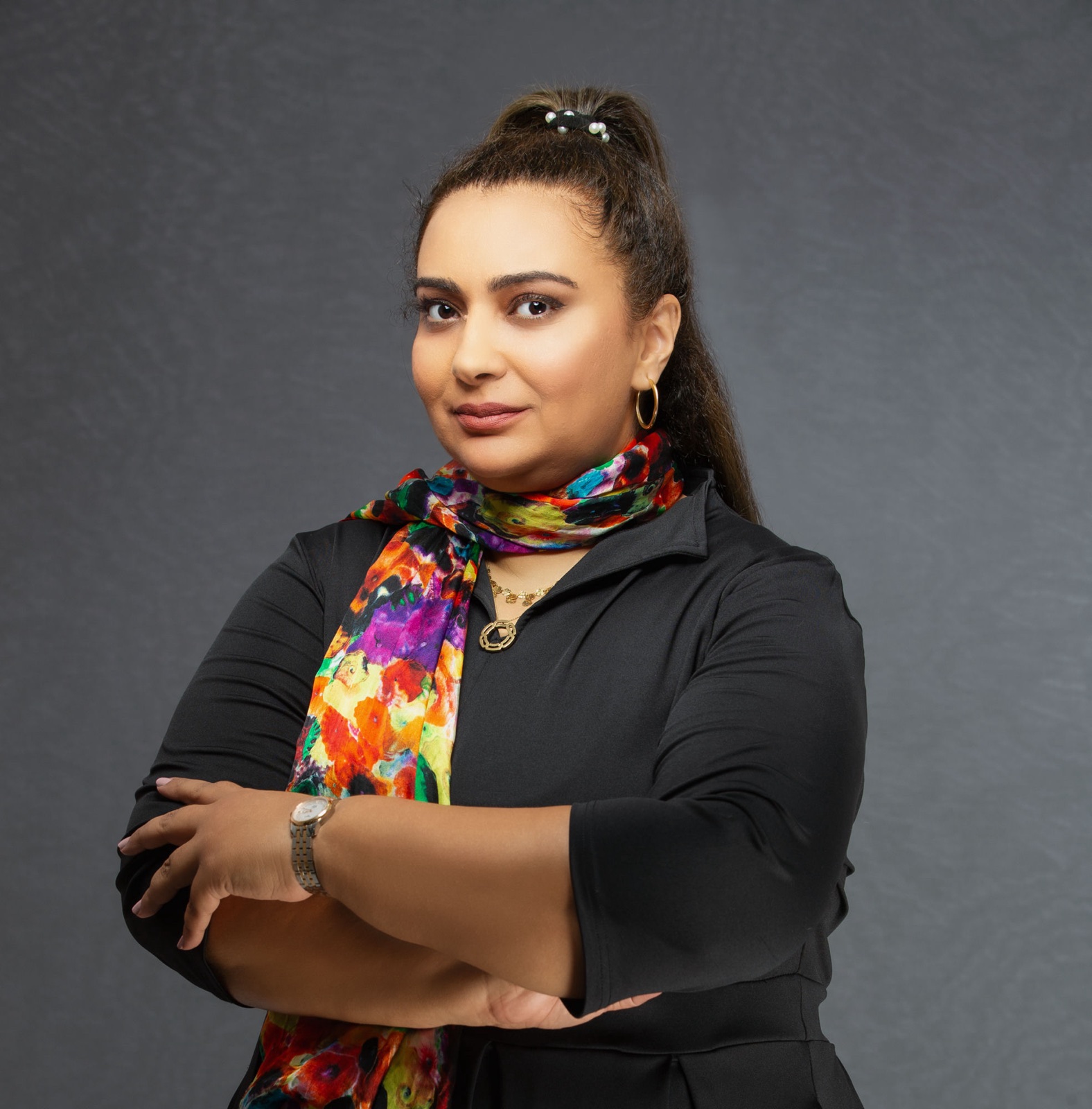 Studio portrait of Nahla ElBanhawy, arms folded, wearing a black top and a painted silk scarf